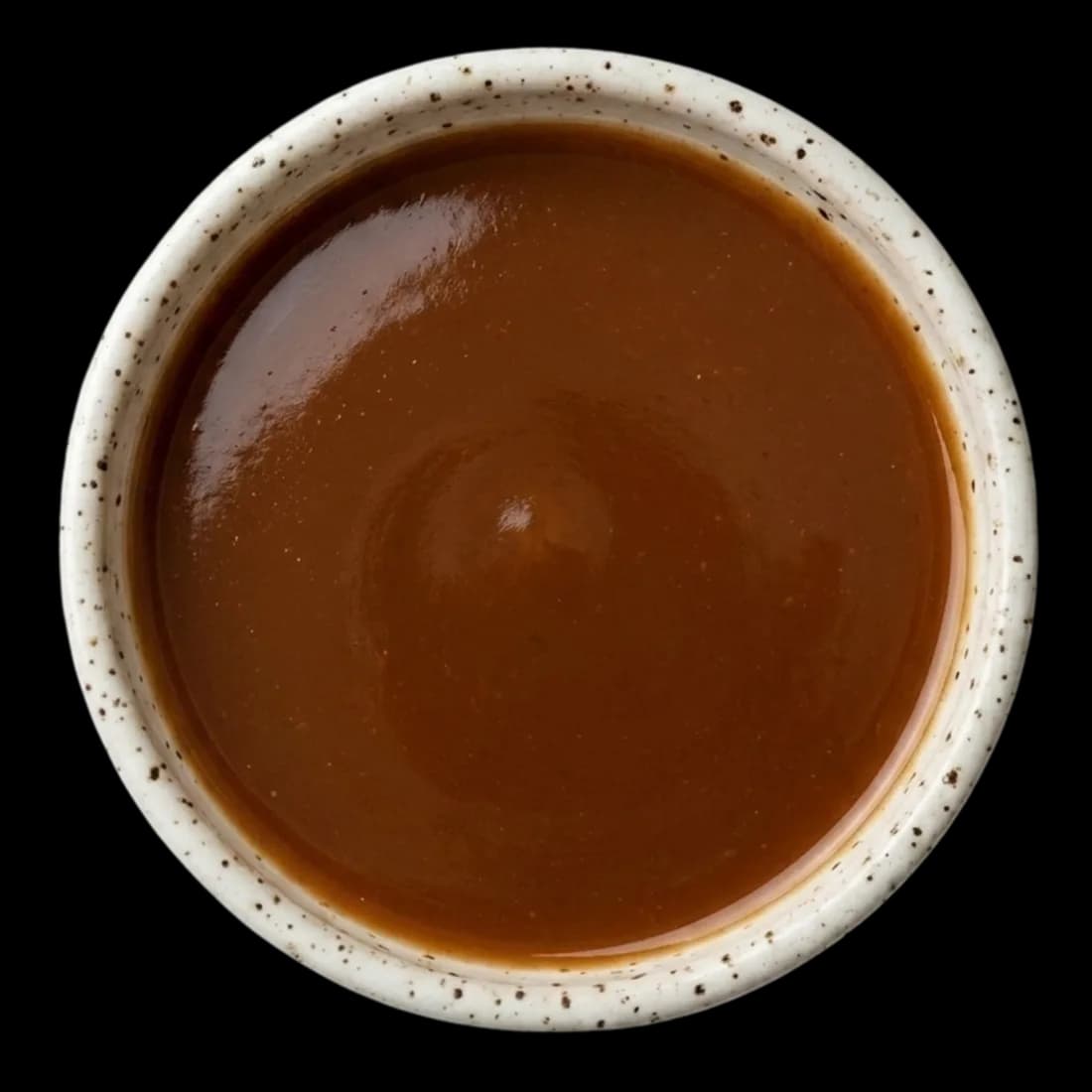 Imli tamarind sauce being poured over lavashak pieces in a serving box